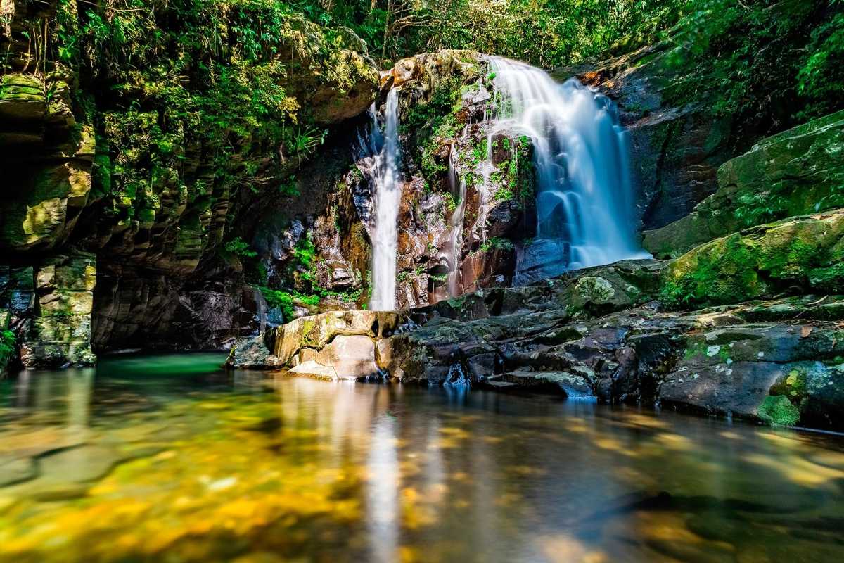 Serene Double Waterfall and Rocky Stream in Bach Ma Two-tier waterfall cascading into a peaceful stream surrounded by mossy rocks and dense jungle in Bach Ma National Park