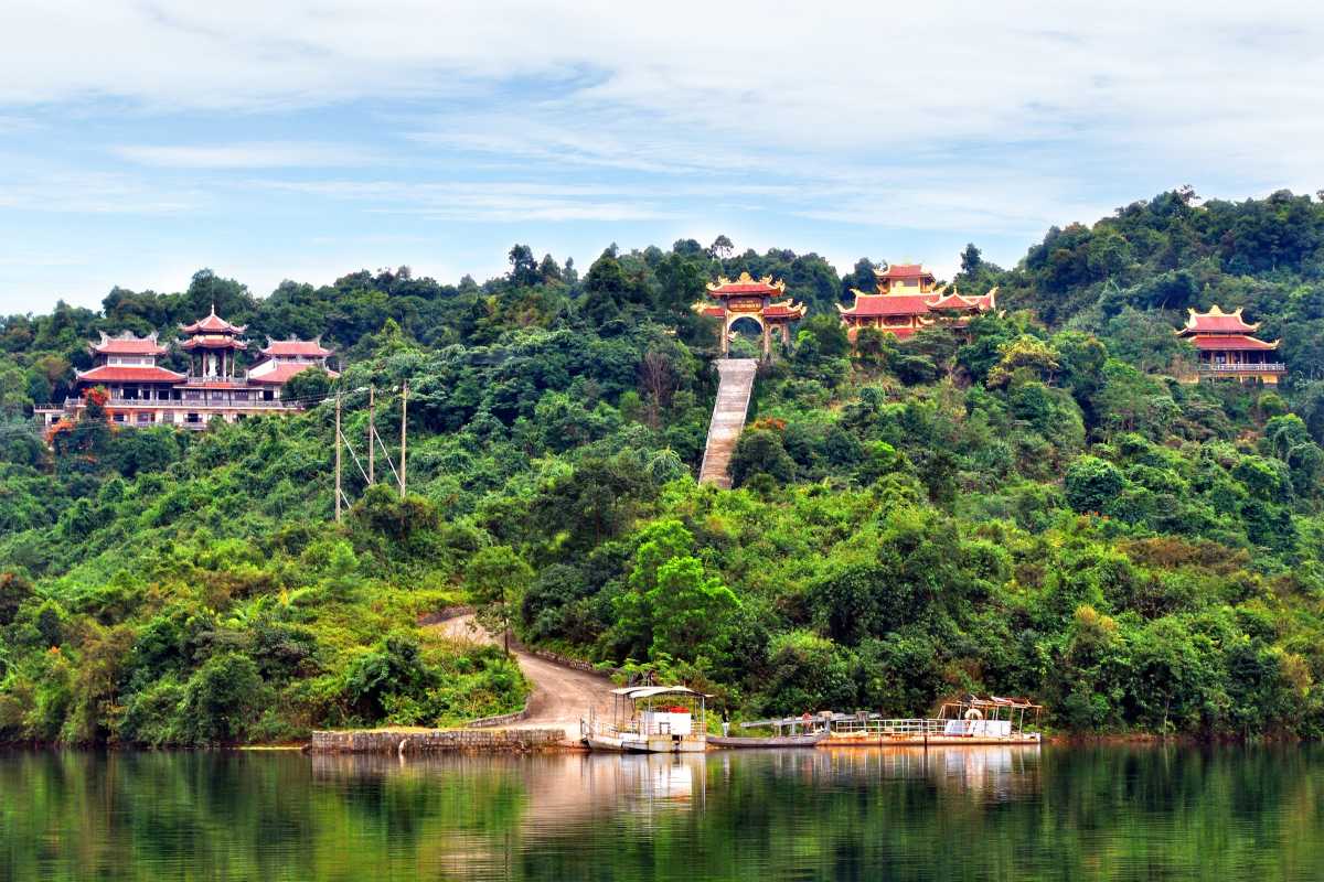 Bach Ma National Park Scenic Lake and Temple View Elevated view of lush green hills and traditional temple buildings overlooking a calm lake at Bach Ma National Park