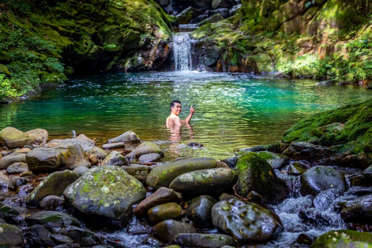 Invigorating Swim in Bach Ma National Park Water Pool Man enjoying a swim in a clear natural pool by a waterfall in the lush forest of Bach Ma National Park