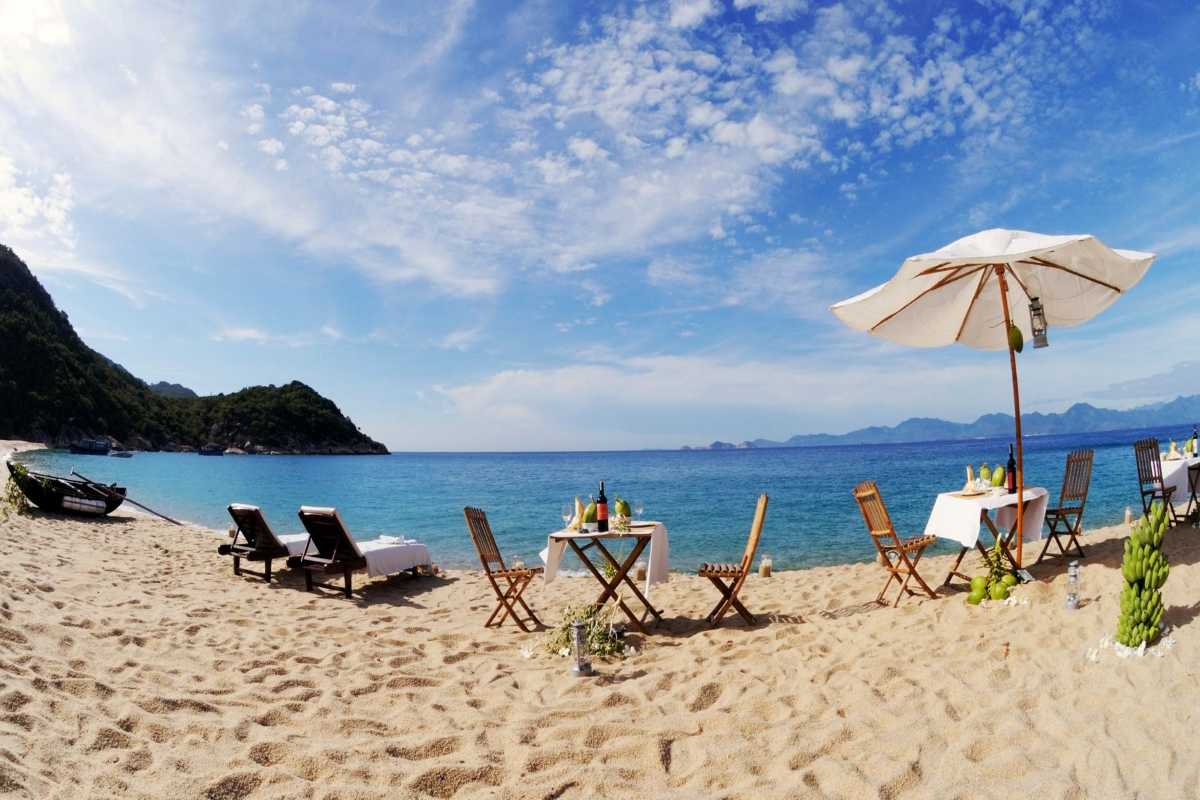 Bai Dai Beach Nha Trang Beachfront Dining Setup Beachfront dining tables and chairs set up with umbrellas on Bai Dai Beach Nha Trang offering scenic ocean views.