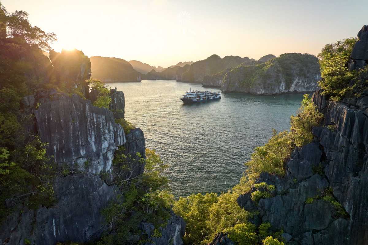 Bai Tu Long Bay Vietnam limestone cliff harbor Limestone cliff harbor in Bai Tu Long Bay Vietnam with boats anchored near towering green cliffs.