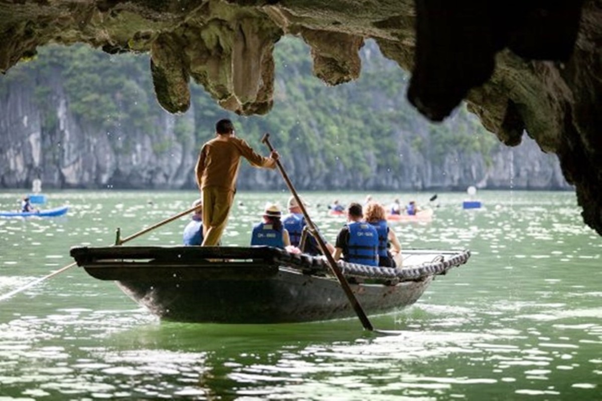 A bamboo boat ride through Luon Cave in Halong Bay, showcasing stunning limestone cliffs and tranquil waters.