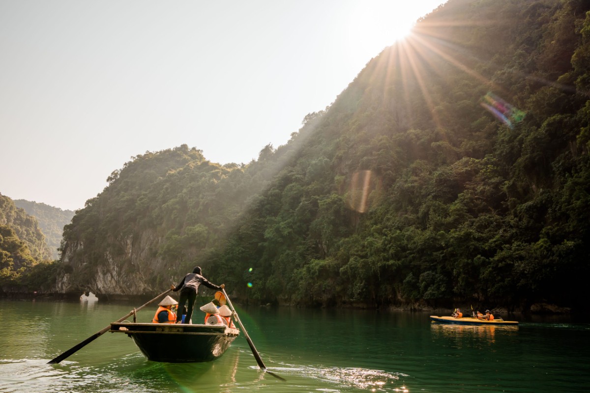 A tranquil bamboo boat ride in Halong Bay with limestone cliffs.