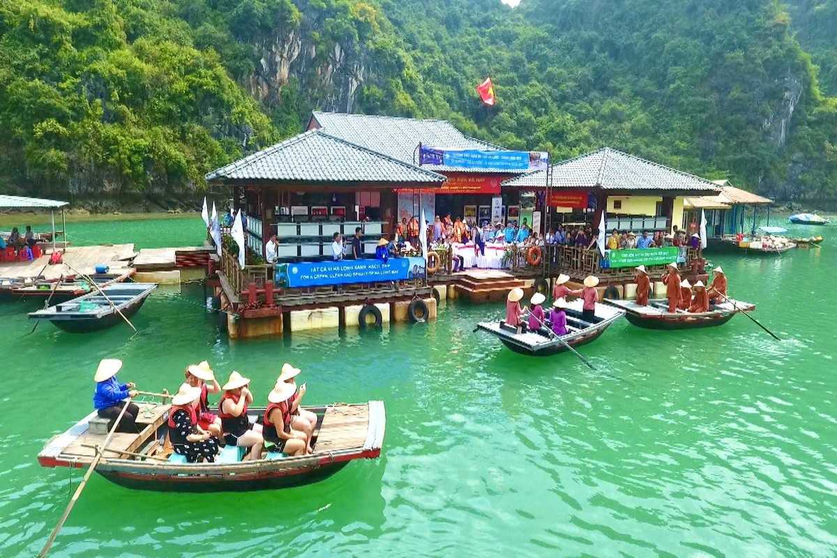 Bamboo Boat Ride at Ba Hang Fishing Village Tourists enjoy a bamboo boat ride guided by locals in Ba Hang Fishing Village, surrounded by green waters and limestone cliffs in Halong Bay.