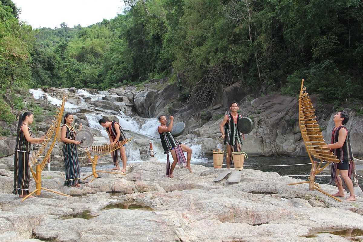 Traditional bamboo music performance Ethnic men and women play bamboo xylophones and gongs by a riverside waterfall in Nha Trang.