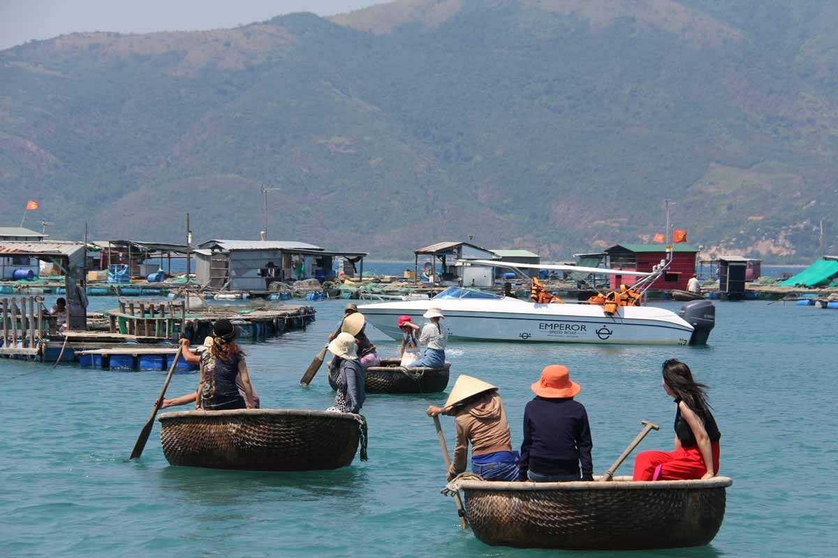 Basket boats and Emperor Cruise at Cau Da Locals paddle basket boats near Cau Da Port Nha Trang alongside an Emperor Cruise speedboat.