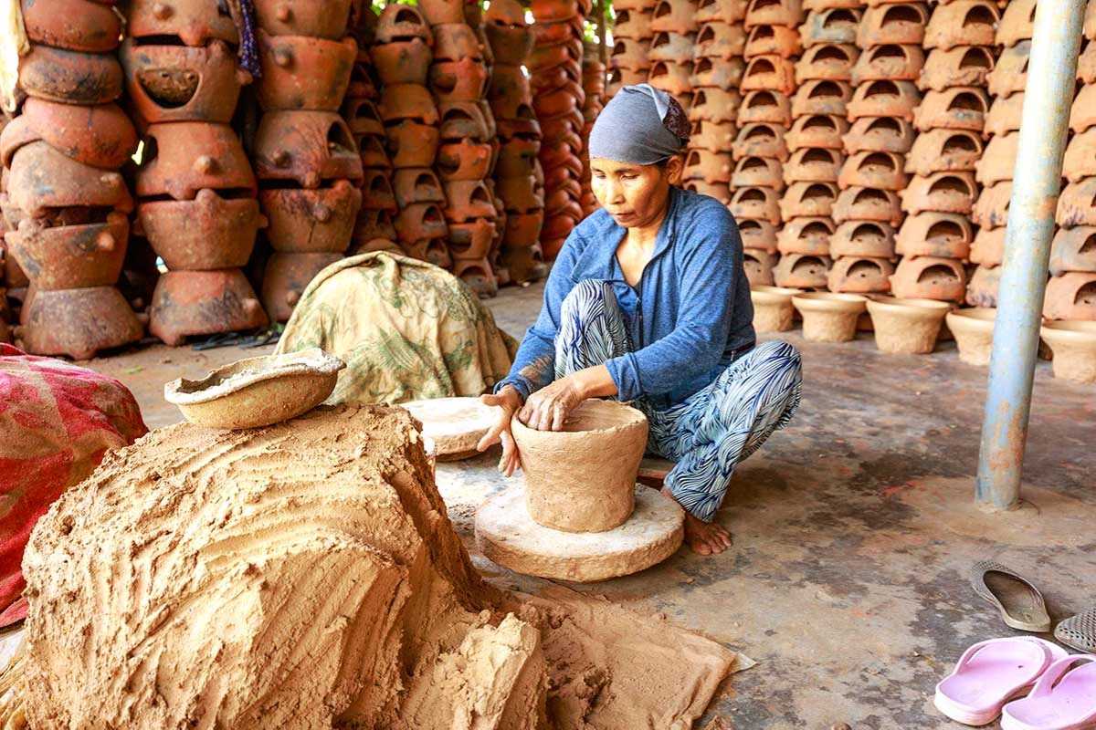 Artisan Shaping Clay Pots in Bat Trang Ceramic Village Skilled artisan shaping clay pots by hand at Bat Trang Ceramic Village, surrounded by terracotta products