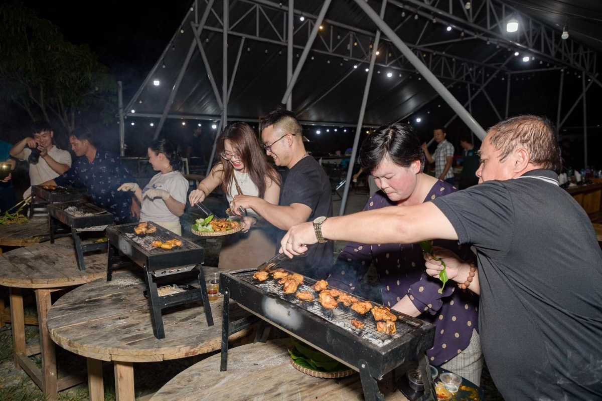 Outdoor BBQ activity in Khanh Vinh Group of tourists grilling food at a cultural evening BBQ in Khanh Vinh town