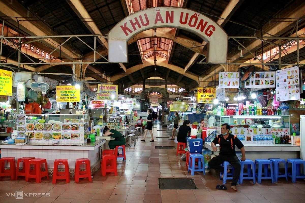 Ben Thanh Market food court area with colorful signage Food court area inside Ben Thanh Market featuring various Vietnamese dishes and seating arrangements