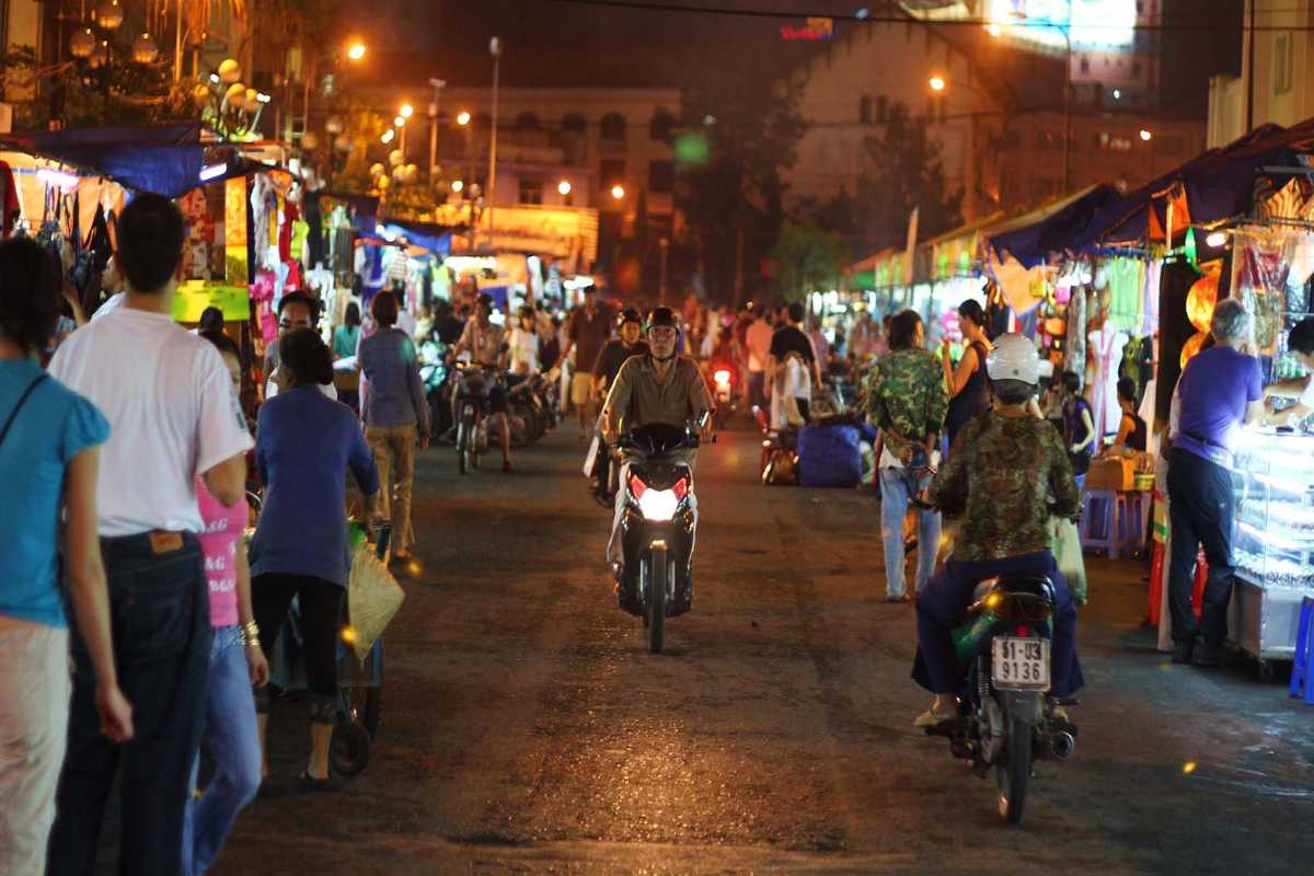 Ben Thanh Market night market bustling street scene Bustling night market street at Ben Thanh Market filled with shoppers and motorbikes