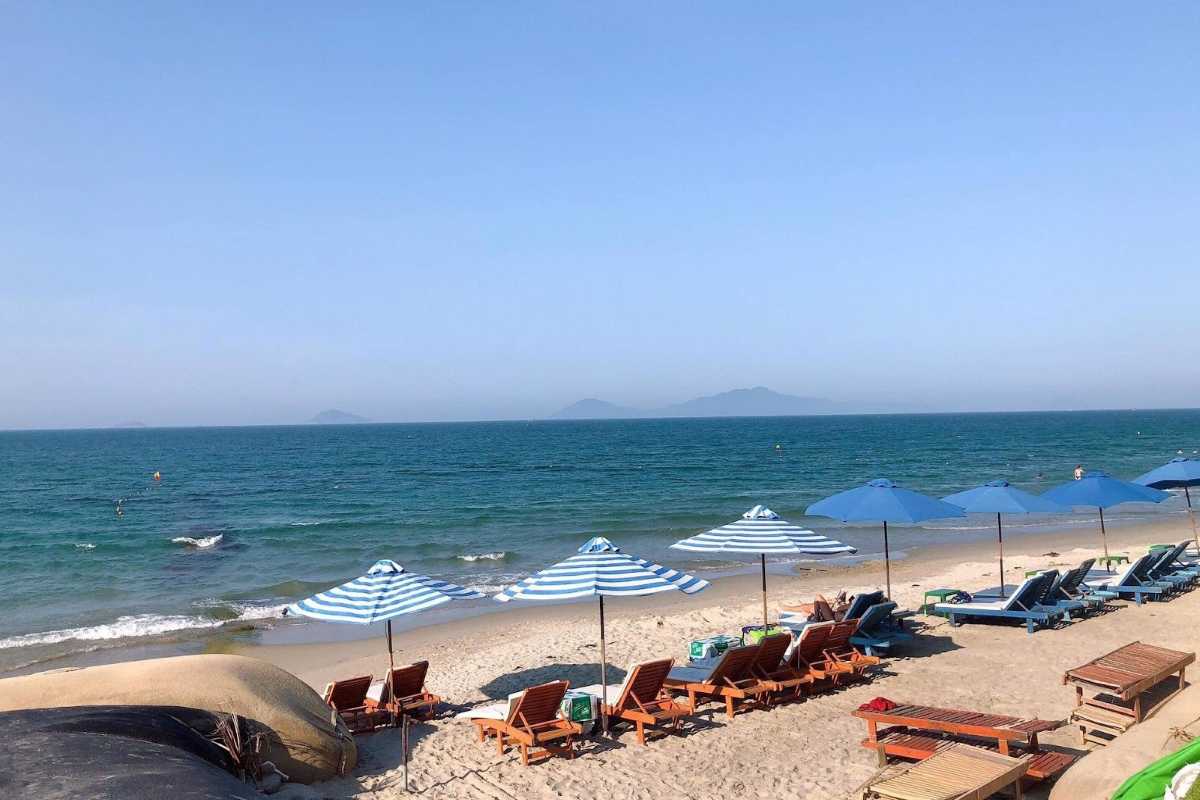 Blue and White Umbrellas Along the Shore of Cua Dai Beach Blue and white striped umbrellas lining the sunny sandy shore of Cua Dai Beach