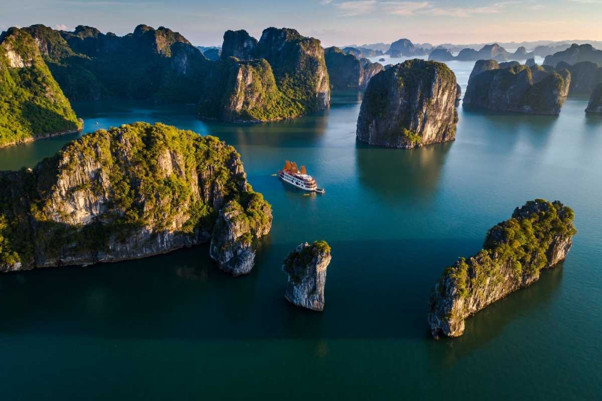 Bo Nau Cave Halong Bay scenic bay view with cruise boat Bo Nau Cave Halong Bay shows towering limestone peaks and a boat cruising through crystal-clear waters.