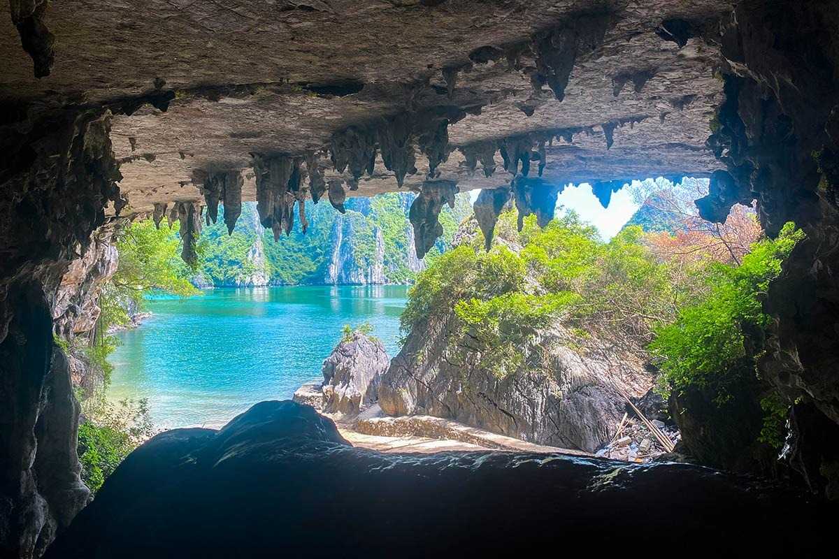 Bo Nau Cave Halong Bay stunning karst formations and a boat A stunning view from Bo Nau Cave in Halong Bay with towering limestone formations and a passing boat.