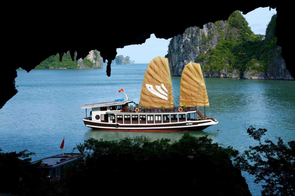 Bo Nau Cave Halong Bay view of traditional boats Traditional boats on the emerald waters of Bo Nau Cave Halong Bay with lush green karsts in the backdrop.