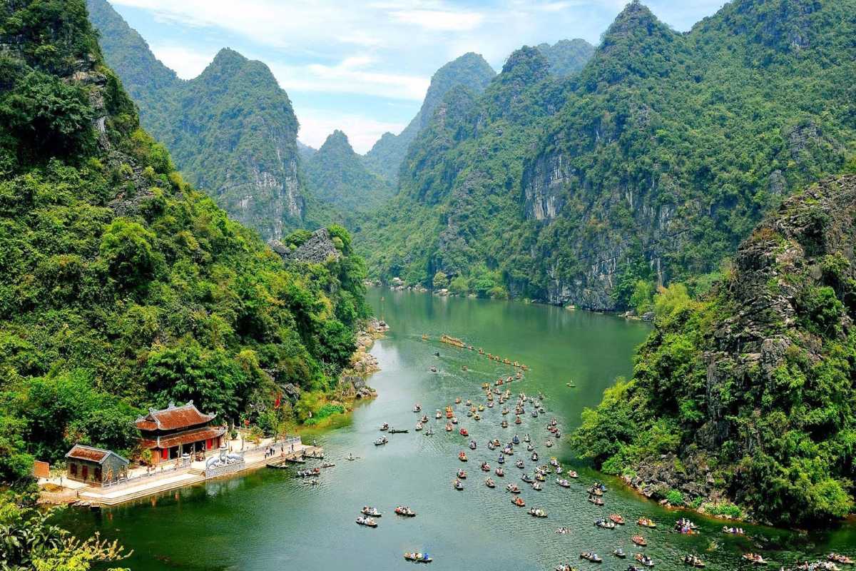 Boat Tour on Trang An Ninh Binh River Through Karst Mountains Numerous boats floating on the river through karst mountains at Trang An Ninh Binh, offering immersive tours