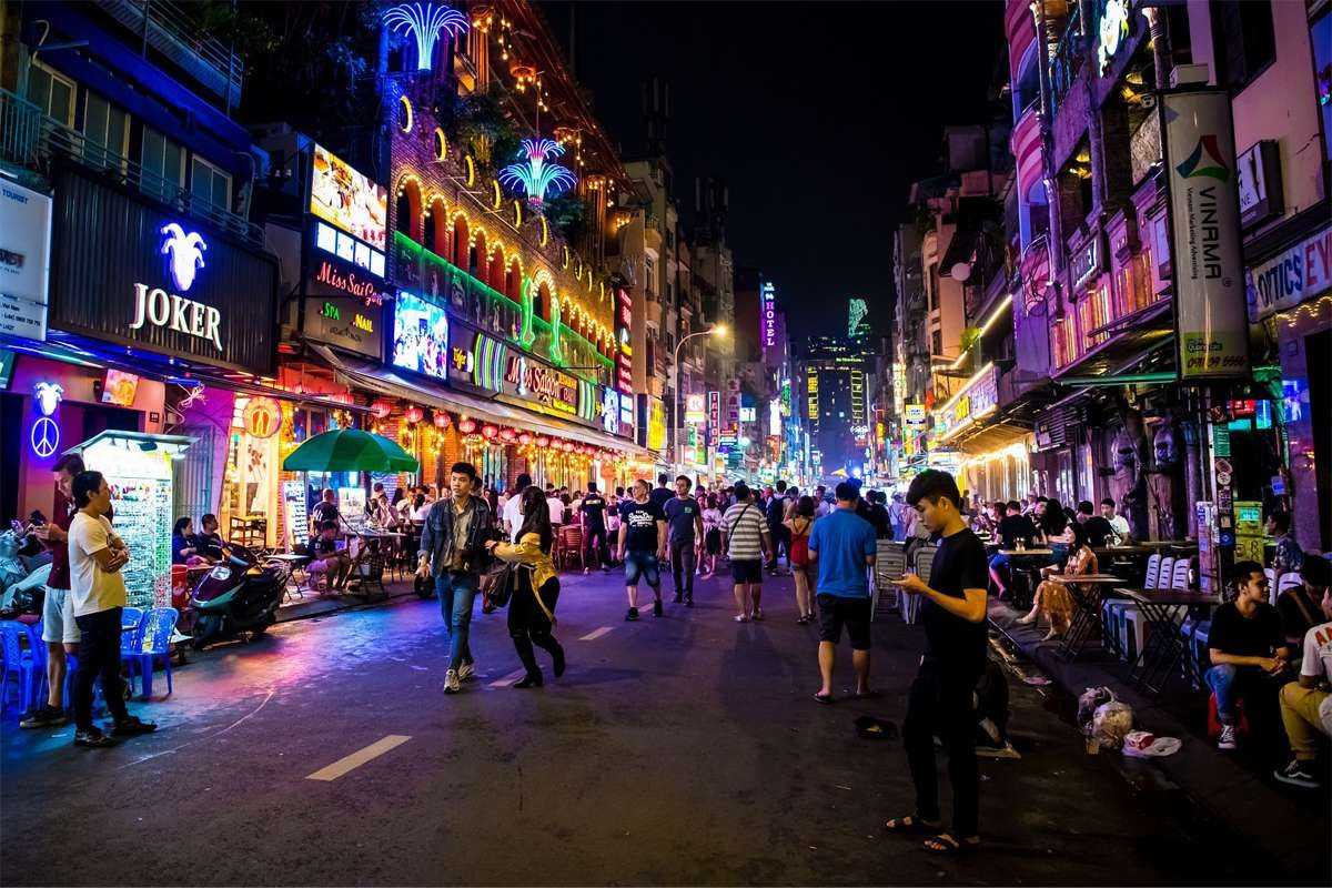 Festive Night Crowds on Bui Vien Street Large crowds enjoying festive nighttime atmosphere on Bui Vien walking street in Saigon.