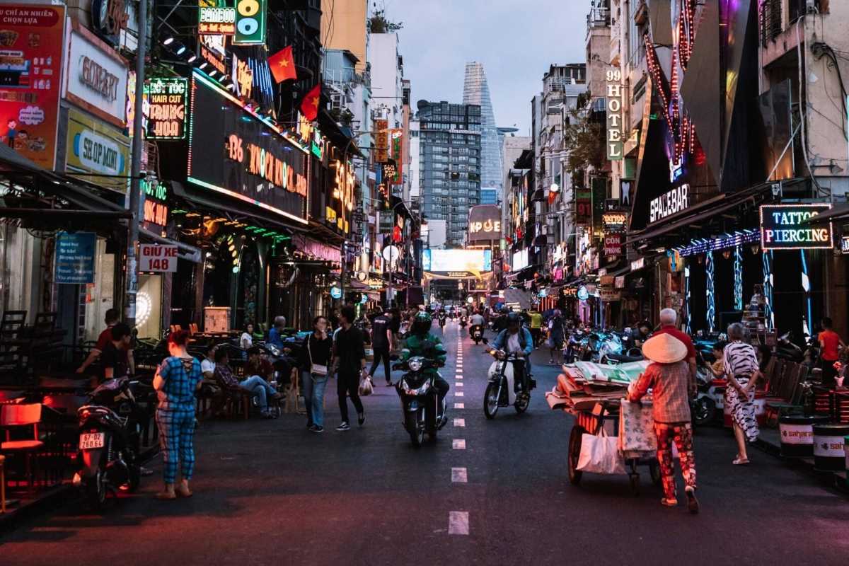 Nighttime Party Scene on Bui Vien Street People socializing outside bars on Bui Vien Street with neon signage in Ho Chi Minh City.