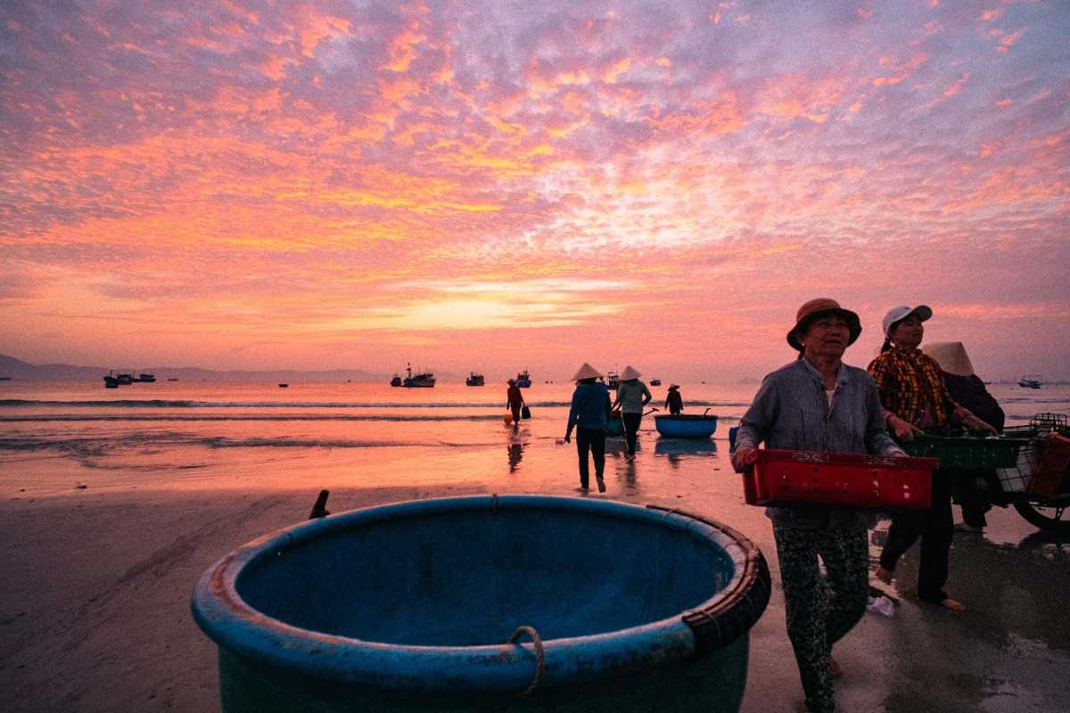 Busy beach market with fishing boats and local vendors at Ninh Thuy Fishing Village Busy beach market scene with fishing boats and local vendors selling seafood at Ninh Thuy Fishing Village