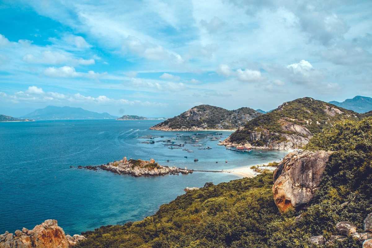 Cam Ranh Bay Coastal Rocky Landscape Rocky coastline and blue waters of Cam Ranh Bay under a partly cloudy sky