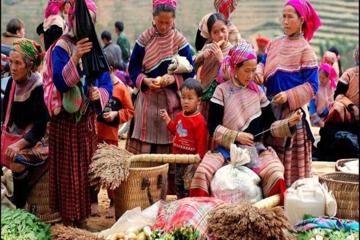 Can Cau Market Lao Cai ethnic women with harvested goods Local women in traditional dress display harvested produce and herbs for sale at Can Cau Market Lao Cai