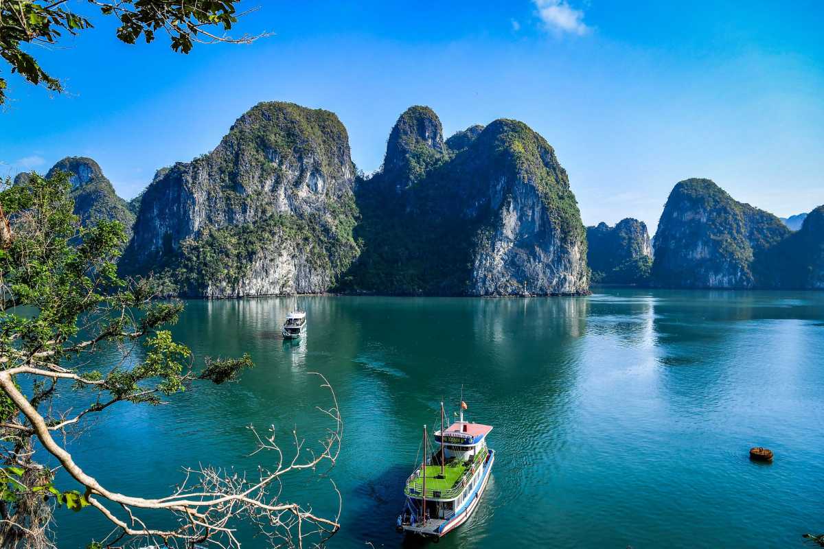 Cap La Island Bai Tu Long Bay Kayaking Adventure Tourists kayaking in calm waters around Cap La Island in Bai Tu Long Bay surrounded by limestone karsts