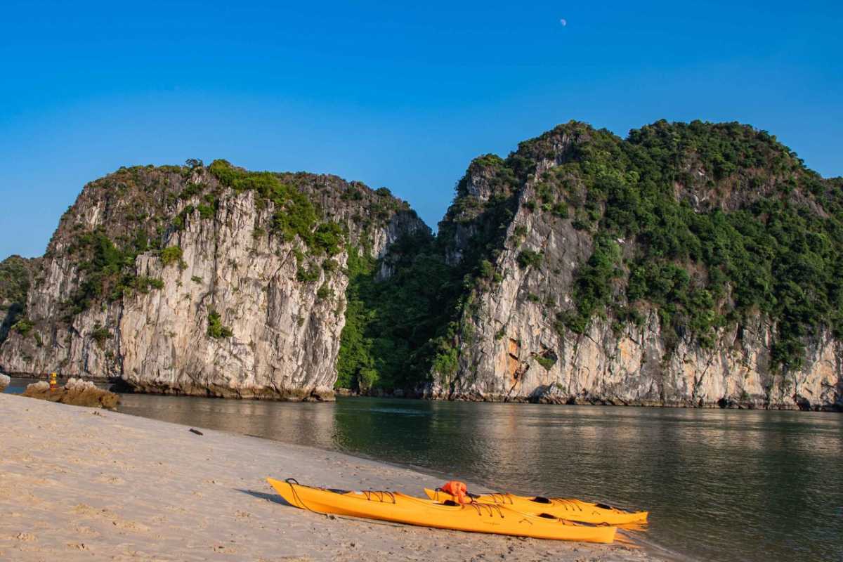 Kayaks on the Beach at Cap La Island Bai Tu Long Bay Kayaks resting on the sandy beach at Cap La Island with limestone cliffs and calm water