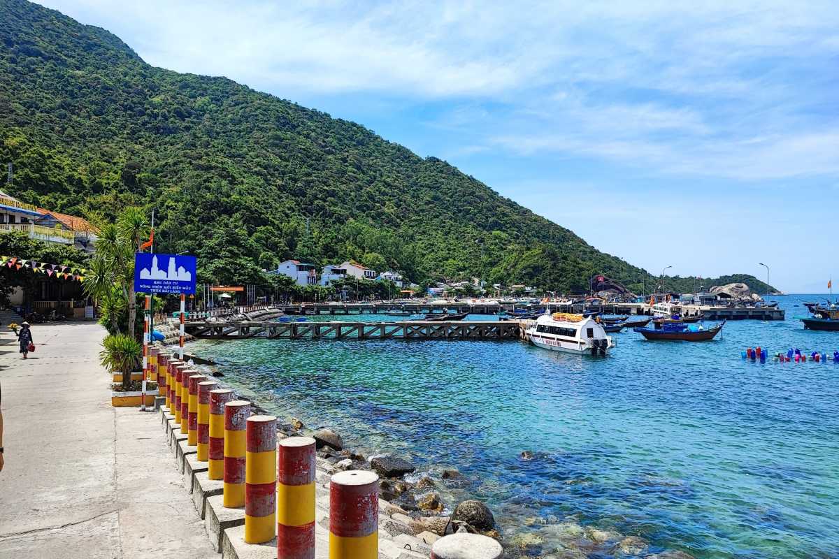Peaceful Beach Scene with Boats and Green Hills Quiet beach area with boats docked and green hills in the background at Cham Islands