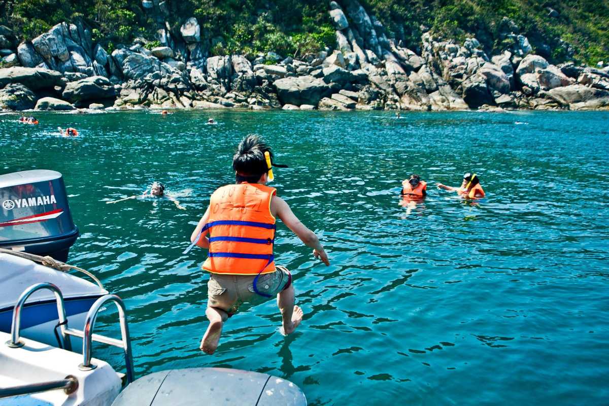 Speedboat Heading to Cham Islands from Mainland White speedboat cruising over blue waters towards Cham Islands surrounded by green hills