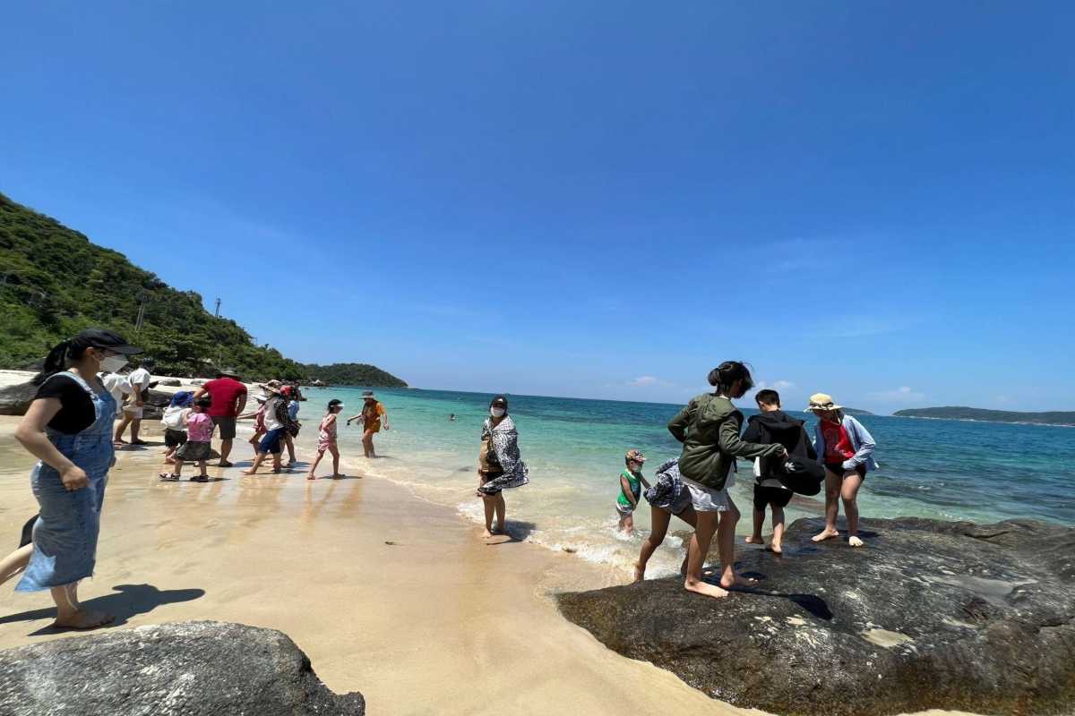 Tourists Enjoying Beach Time at Cham Islands Tourists wading and playing in the shallow waters on a sandy beach of Cham Islands under clear skies