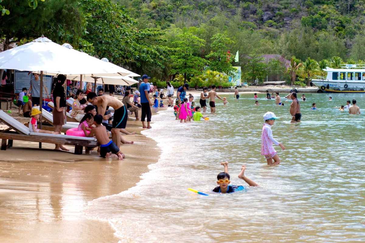 Children Playing on Beach at Orchid Stream Island Nha Trang Kids playing in shallow waters and on sandy beach under sun umbrellas at Orchid Stream Island