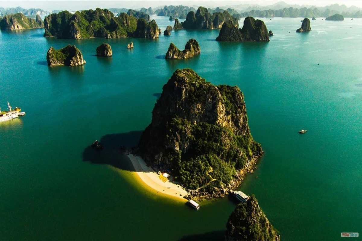 Cho Da Islet Halong Bay beach and boats Cho Da Islet Halong Bay with a sandy beach and boats docked near the lush green limestone cliffs.