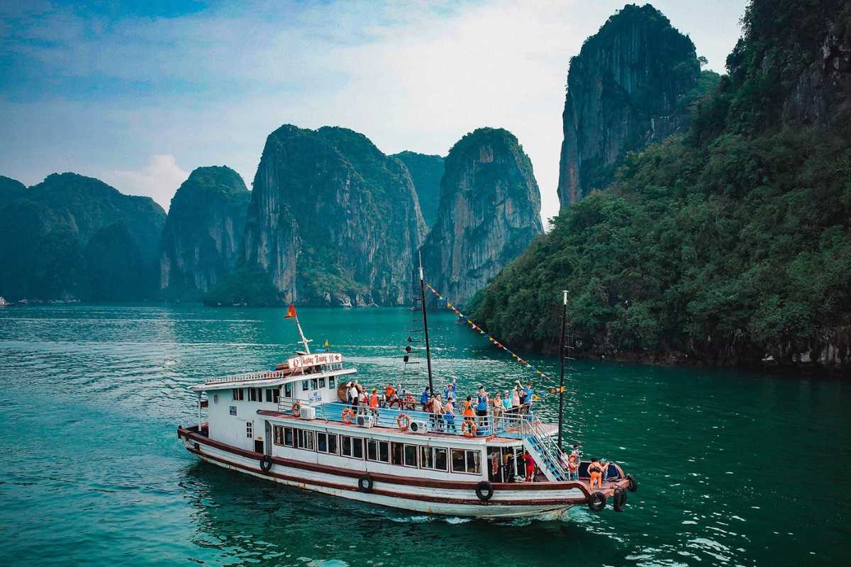 Cho Da Islet Halong Bay traditional rowboat with tourists Traditional rowboat carrying tourists near Cho Da Islet Halong Bay with limestone cliffs in the background.