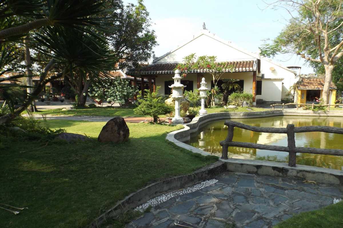 Garden Pond and Statue at Chuc Thanh Pagoda Hoi An Serene garden pond with curved stone railing and white statue surrounded by greenery at Chuc Thanh Pagoda
