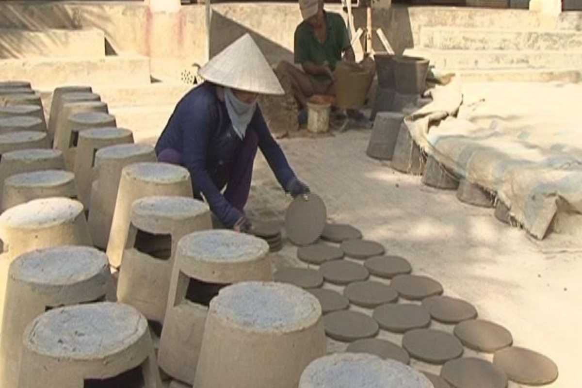 Clay Stove Production by Hand A village woman crafting traditional clay stoves manually in an outdoor workspace along the Cai River near Nha Trang.