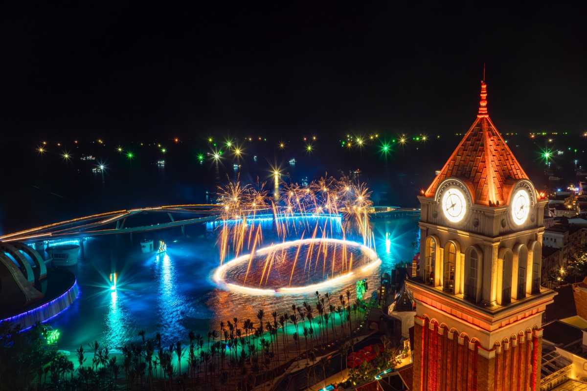 Night view of Clock Tower Phu Quoc illuminated with colorful lights and fireworks by the coast