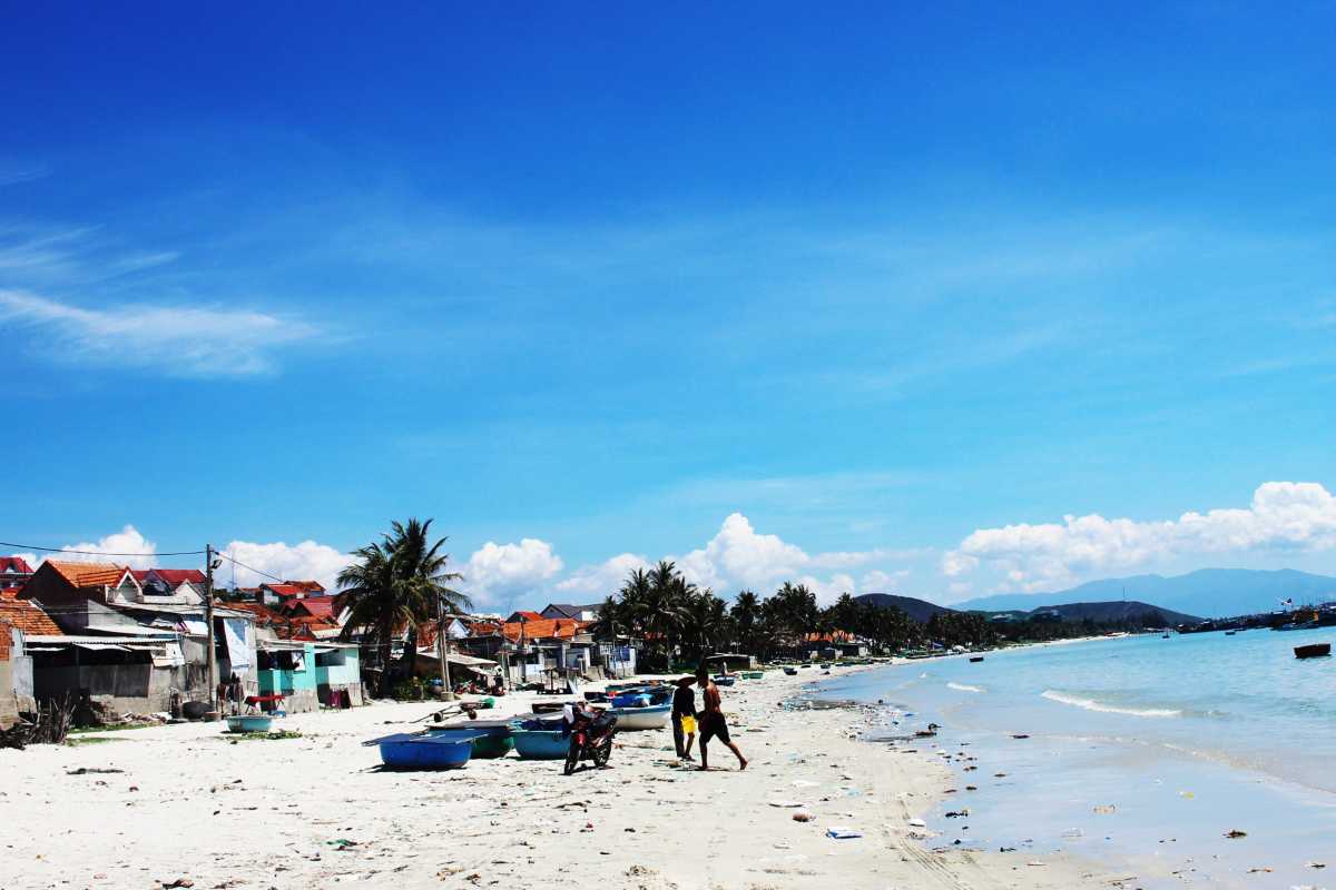 Coastal view of Ninh Thuy Fishing Village with boats on the shore Coastal view of Ninh Thuy Fishing Village showing boats lined along the sandy shore and traditional houses nearby