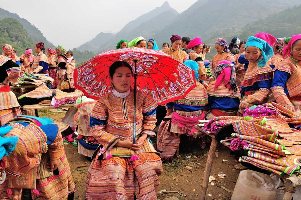 Coc Ly Market Sapa ethnic women red umbrella Coc Ly Market Sapa ethnic women in traditional dresses, one holding a bright red umbrella, gathered at market stalls.