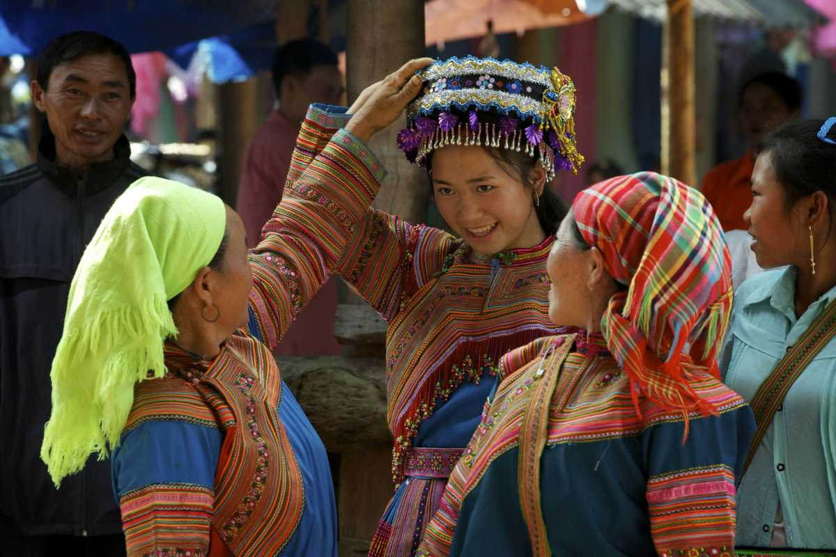 Coc Ly Market Sapa ethnic women vibrant traditional dress Coc Ly Market Sapa ethnic women in colorful traditional dresses, sharing joyful moments in a lively cultural setting.