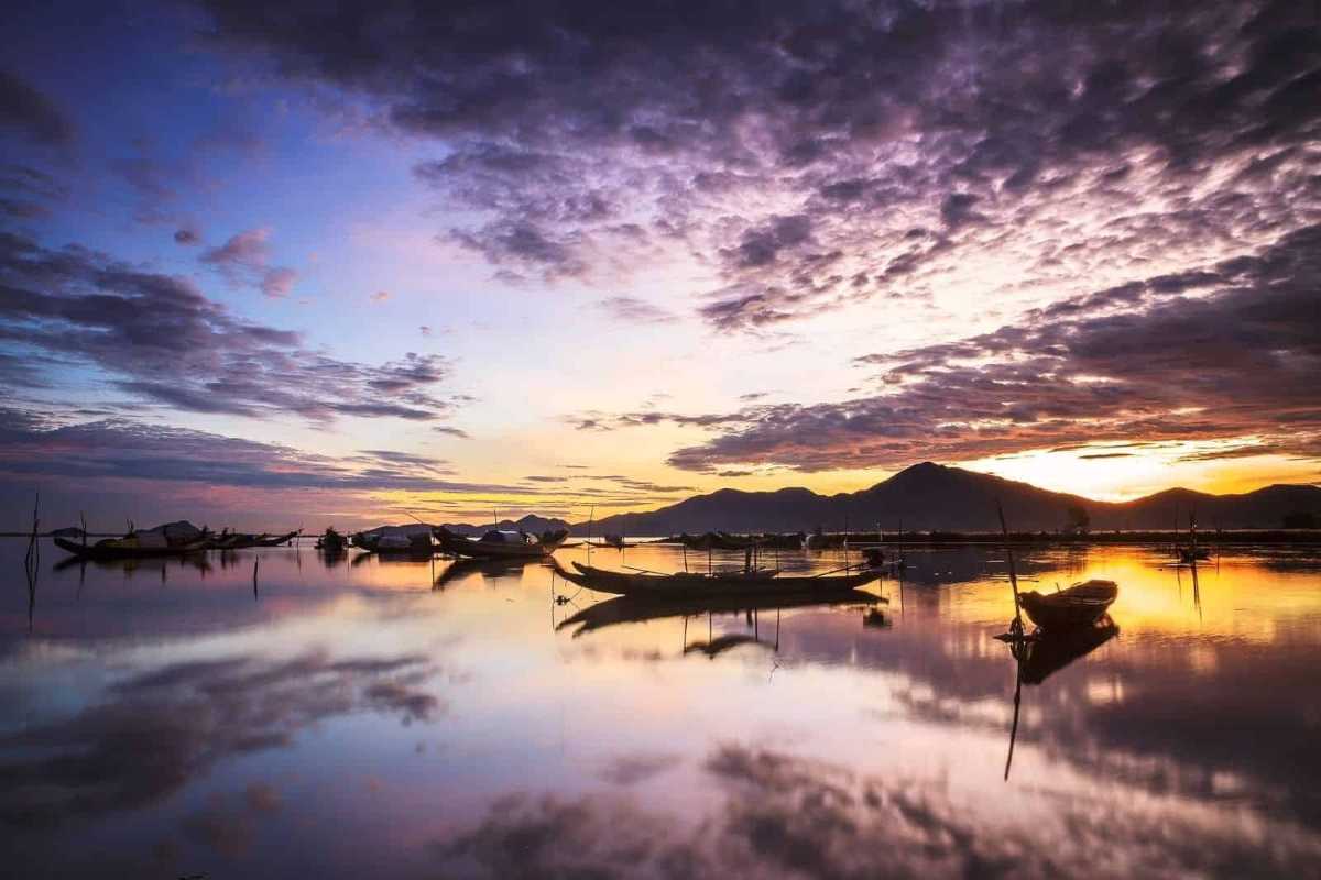 Colorful Boats Floating on Calm Tam Giang Lagoon Brightly colored fishing boats floating on serene waters of Tam Giang Lagoon under a blue sky