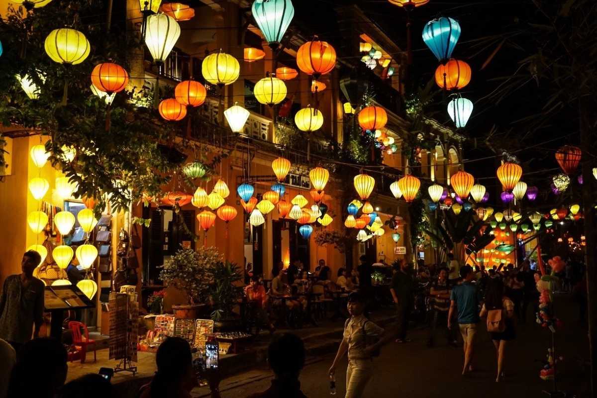 Colorful Lantern Stall with Shoppers at Hoi An Night Market Shoppers browsing colorful lanterns and souvenirs under warm lighting at Hoi An Night Market