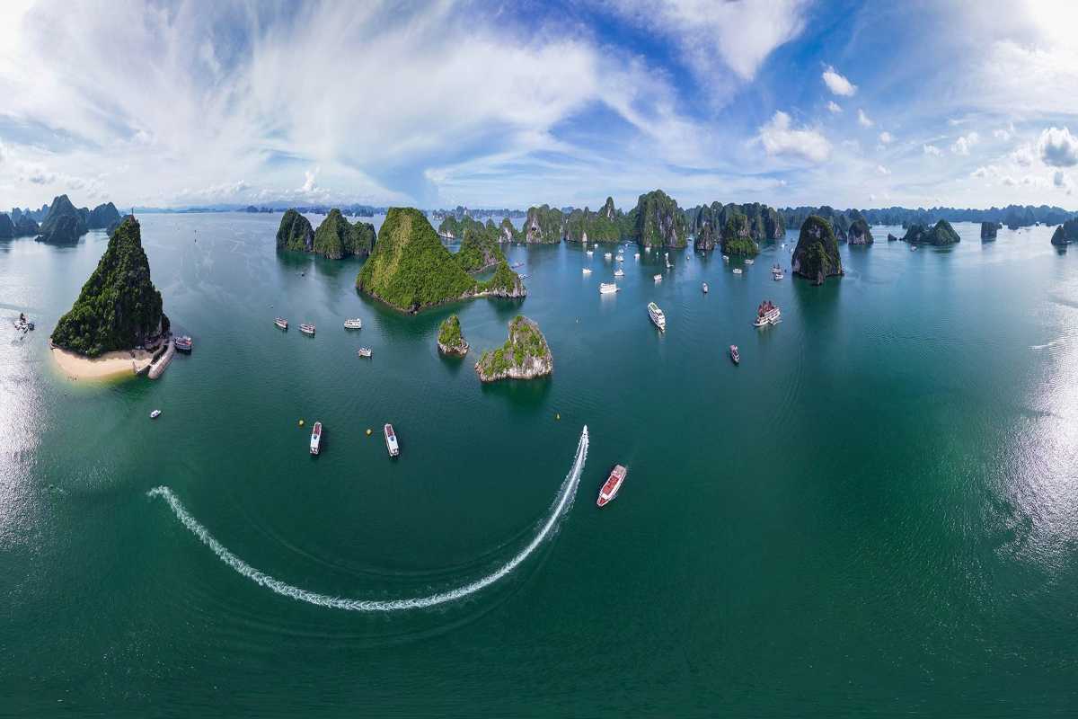 Cong Do Island Bai Tu Long Bay panoramic aerial cruise view Panoramic aerial view of Bai Tu Long Bay with multiple traditional boats cruising near Cong Do Island’s limestone formations