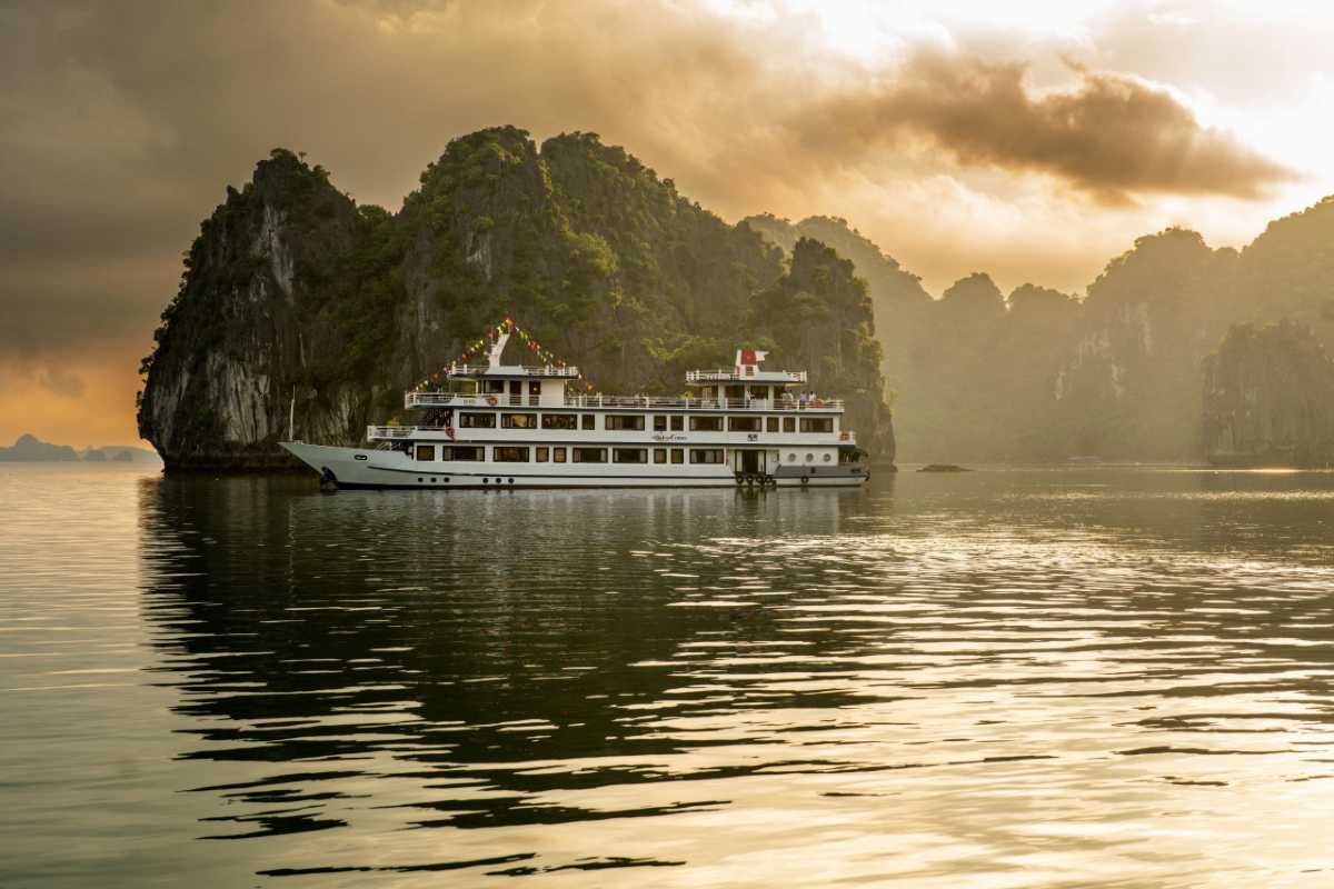 Cong Do Island Bai Tu Long Bay sunset cruise with limestone peaks Sunset cruise with limestone peaks silhouetted against a vibrant sky at Cong Do Island Bai Tu Long Bay