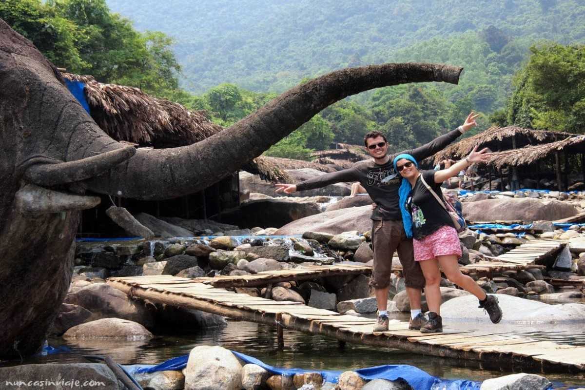 Couple at elephant statue bridge in Hue Couple smiling and posing beneath the trunk of an elephant-shaped rock at Elephant Springs in Hue