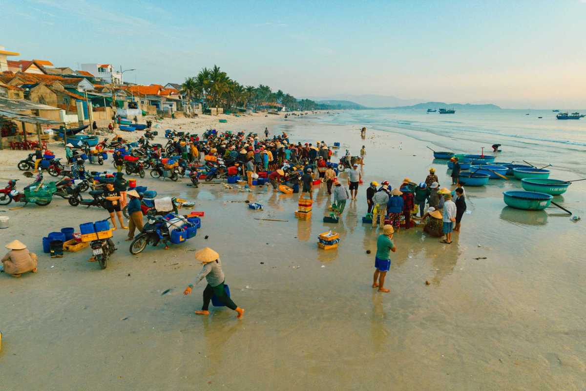 Crowded beach market scene at Ninh Thuy Fishing Village Crowded beach market at Ninh Thuy Fishing Village with locals selling fresh fish and seafood baskets