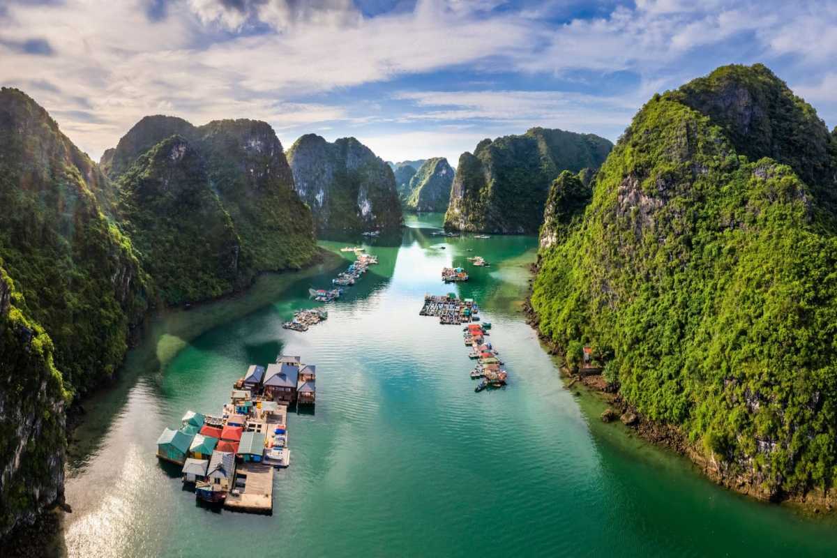 Aerial View Cua Van Floating Village Halong Bay scenic layout Aerial view of Cua Van Floating Village in Halong Bay showing floating homes and turquoise waters framed by towering limestone cliffs