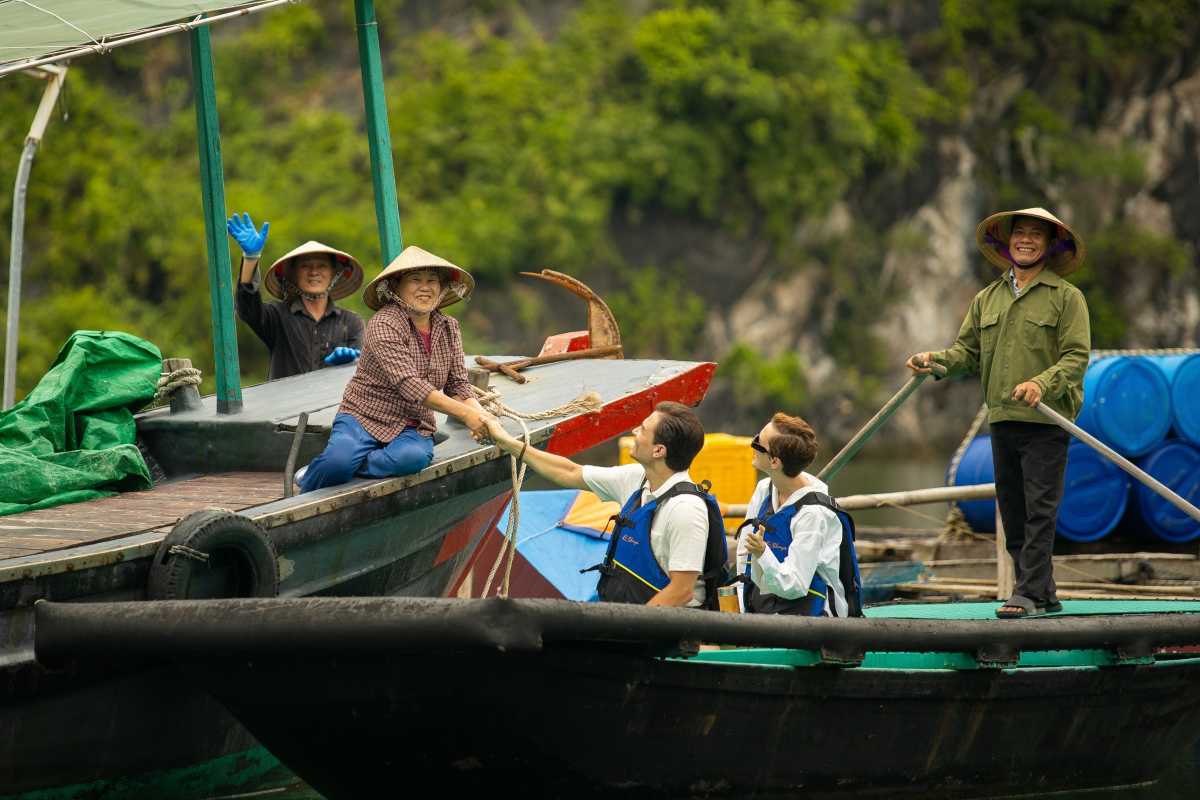 Cua Van Floating Village Halong Bay Friendly Locals Smiling locals on a boat welcoming visitors to Cua Van Floating Village Halong Bay surrounded by natural beauty