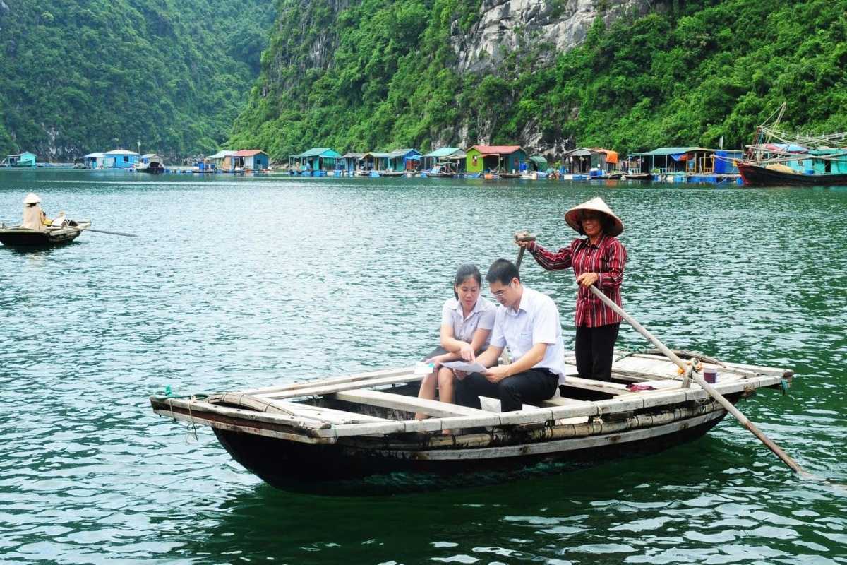 Bamboo Boat and Local Guide in Ba Hang Village Two travelers in business attire are guided through calm waters on a bamboo boat by a local woman in Ba Hang.