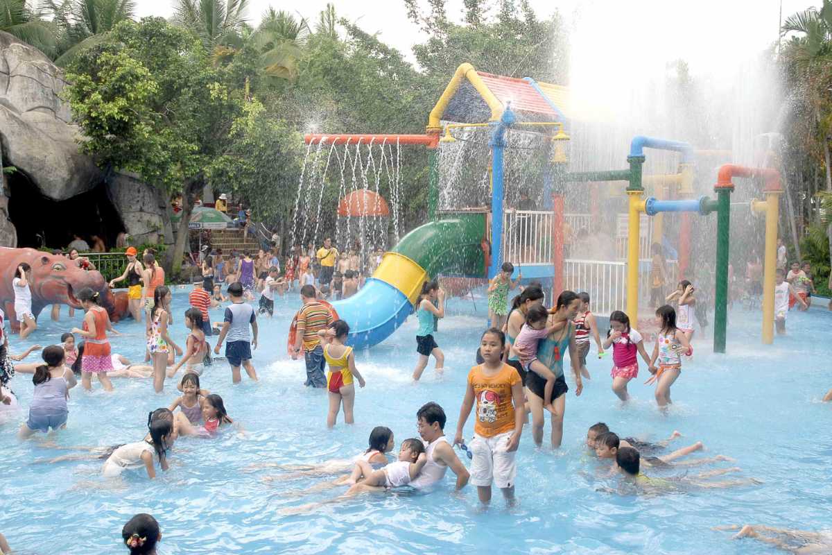 Crowded Water Play Area with Slides and Sprays Families and kids playing in the busy water playground with colorful slides and spray features at Dam Sen Water Park