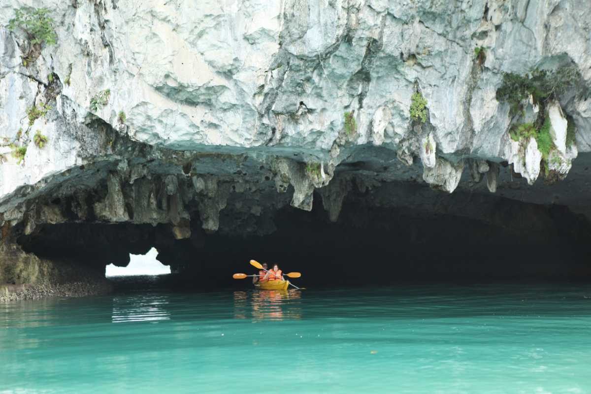 Dark and Bright Cave Halong Bay seen from a kayak, showing limestone archway and emerald waters at the entry