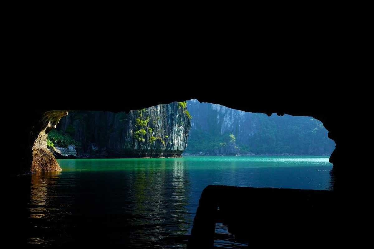 Dark and Bright Cave Halong Bay lagoon light and color View out from inside Dark and Bright Cave Halong Bay, blue-green waters and sunlight highlighting cave entrance